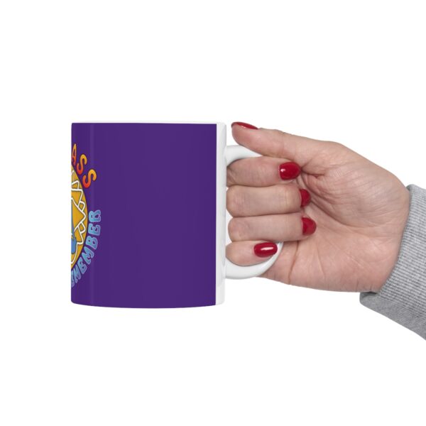 A hand holding a purple mug with a picture of a person.